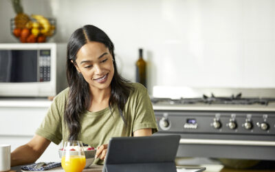 Woman smiling at a tablet on her kitchen counter beside a glass of orange juice